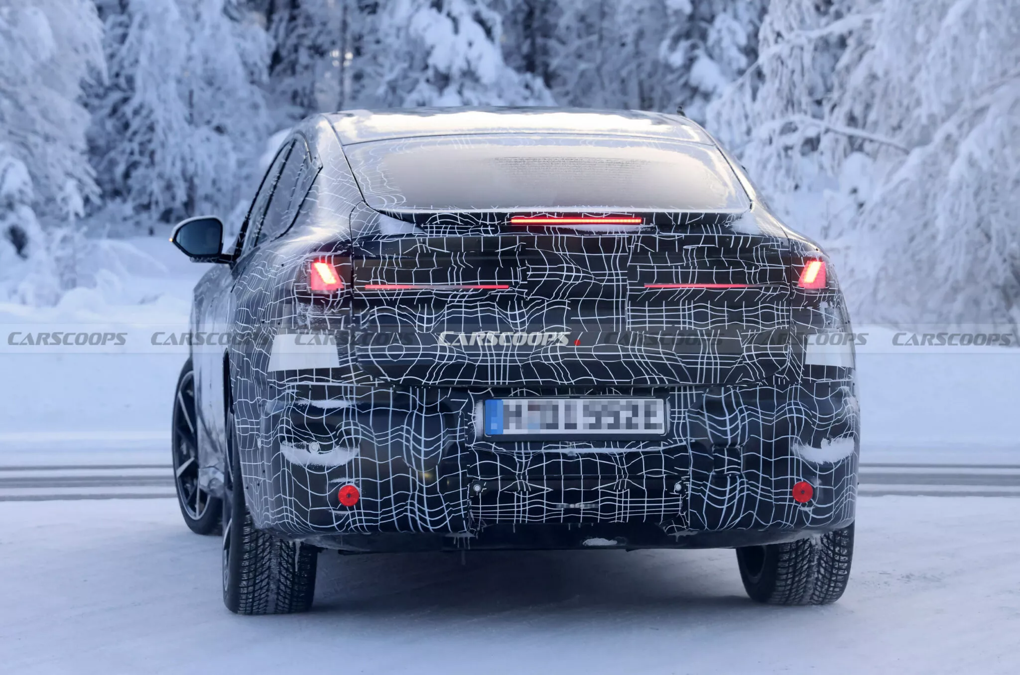 BMW iX4 zezadu — strmě klesající střešní linie a integrovaný zadní spoiler odlišují elektrické kupé od iX3 SUV