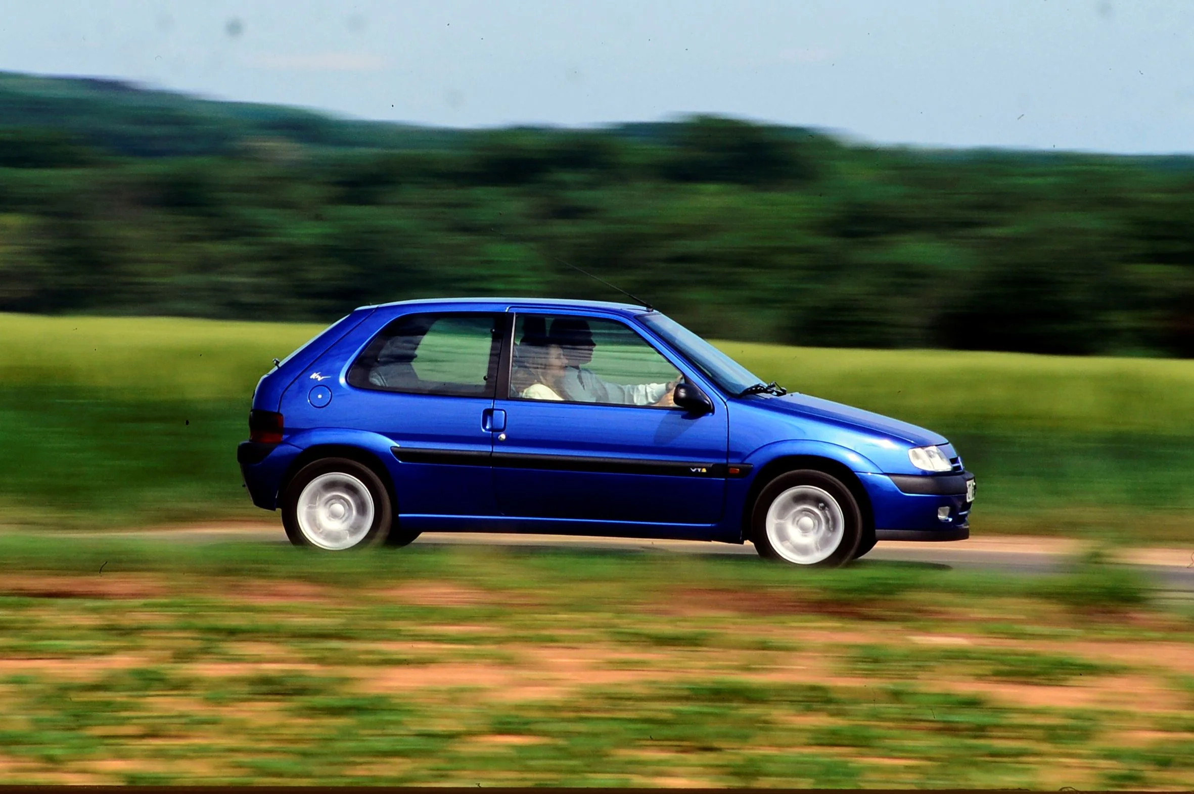 Modrý Citroën Saxo VTS v jízdě, boční pohled, otevřený francouzský venkov