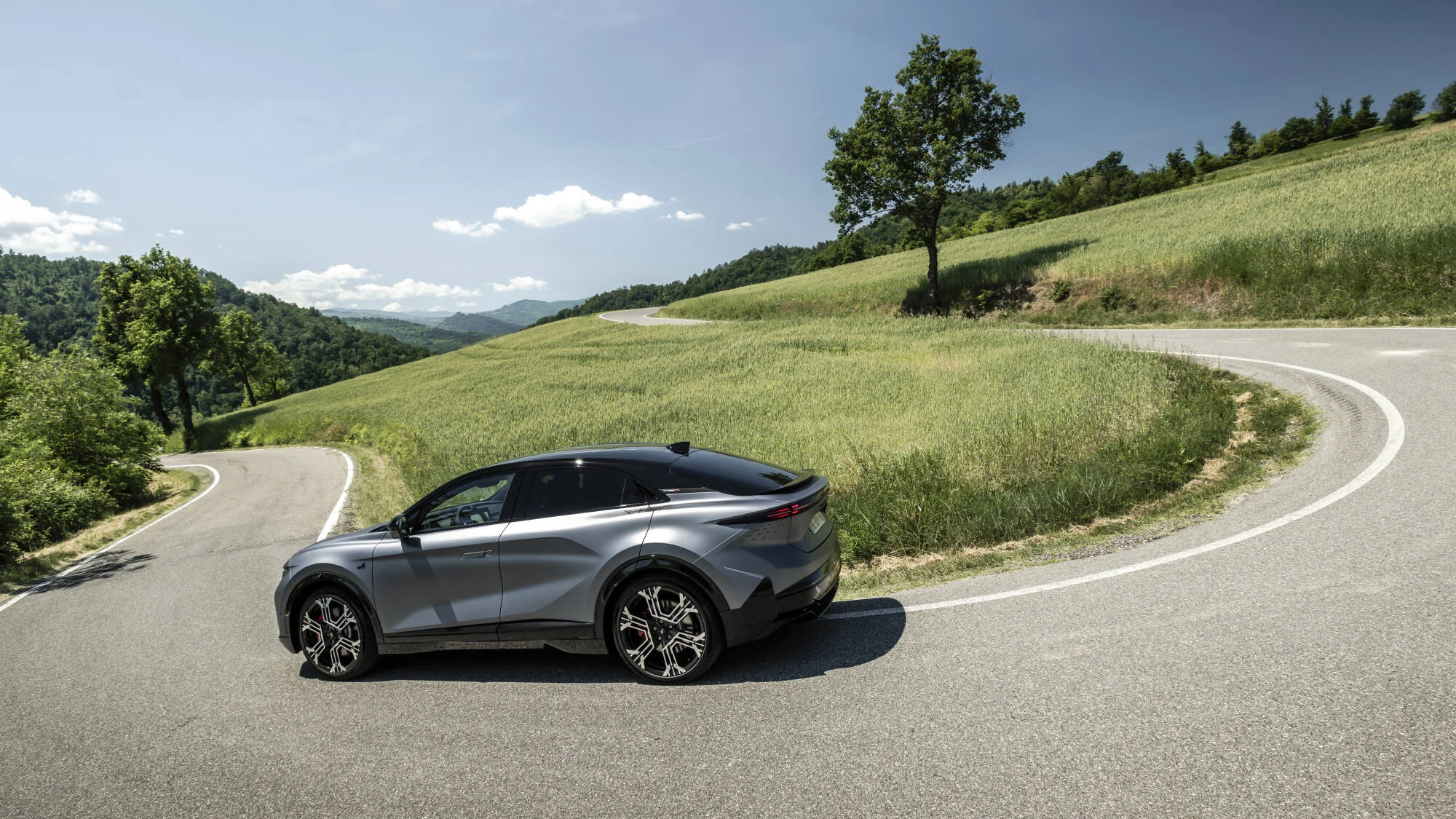 Alpine A390 GTS w matowej szarości Gris Tonnerre z boku i od tyłu na górskiej drodze