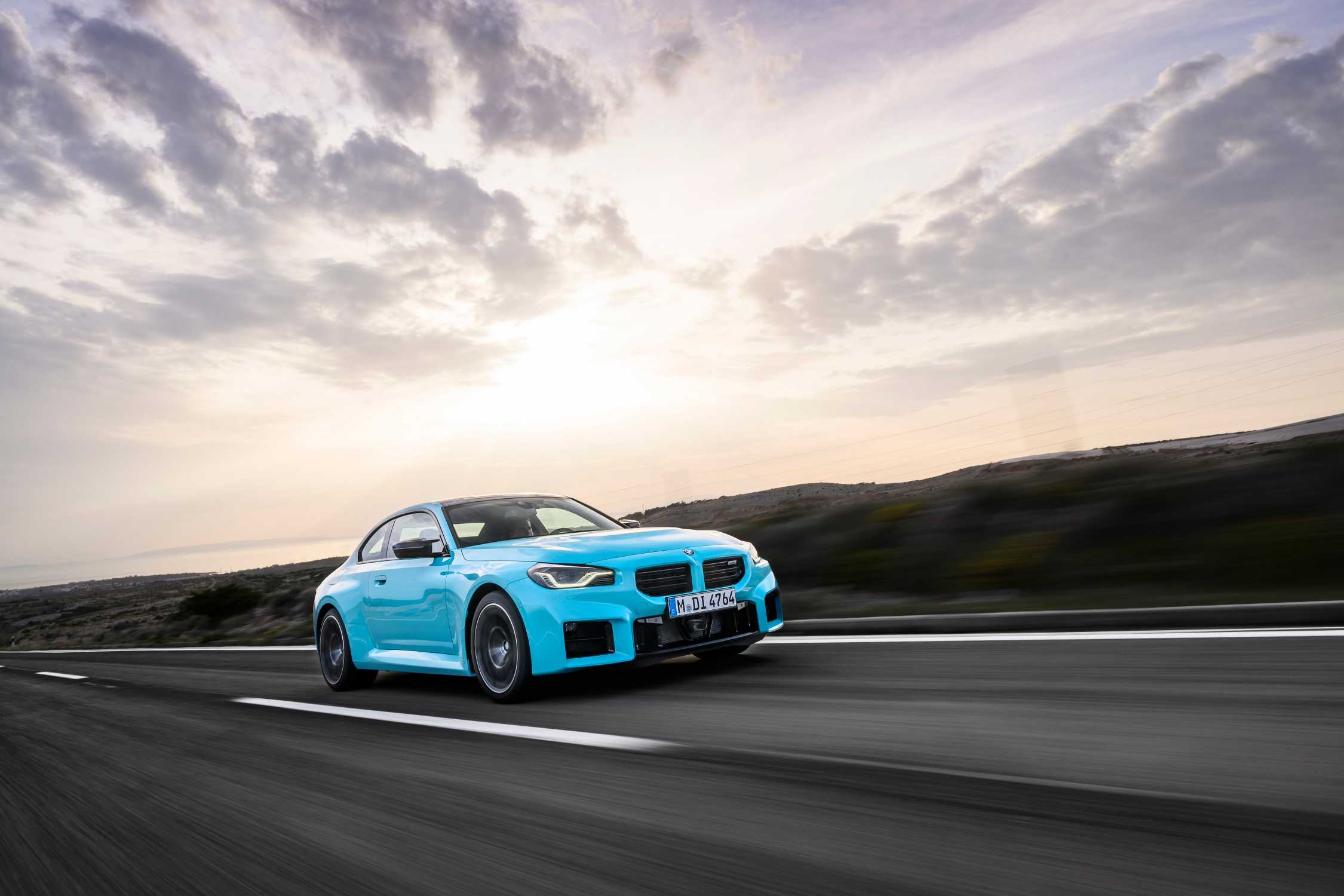 BMW M2 s M xDrive na silnici při západu slunce