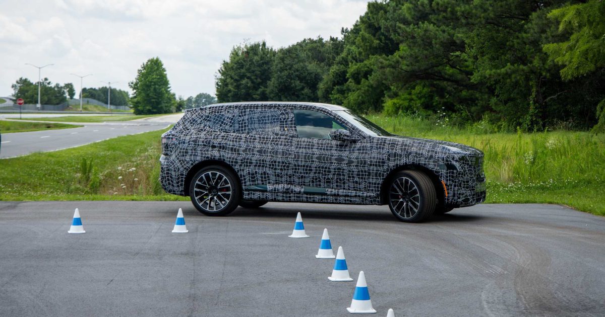 Nové BMW X5 páté generace (prototyp) z boku v maskování na testovací dráze ve Spartanburgu