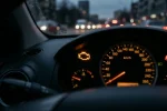 Žlutá kontrolka motoru svítí na přístrojovém štítu auta za soumraku
