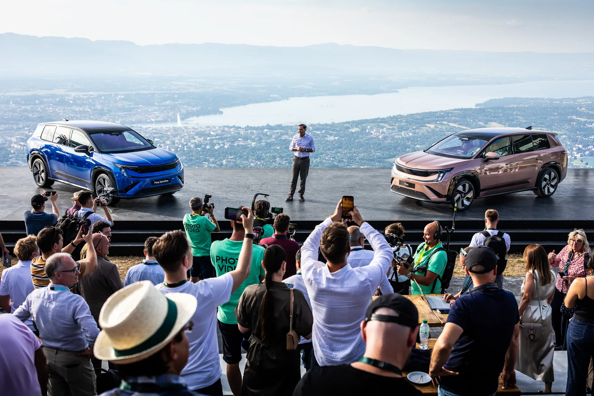 Modrý a růžový Peaq na pódiu světové premiéry s panoramatem Ženevského jezera