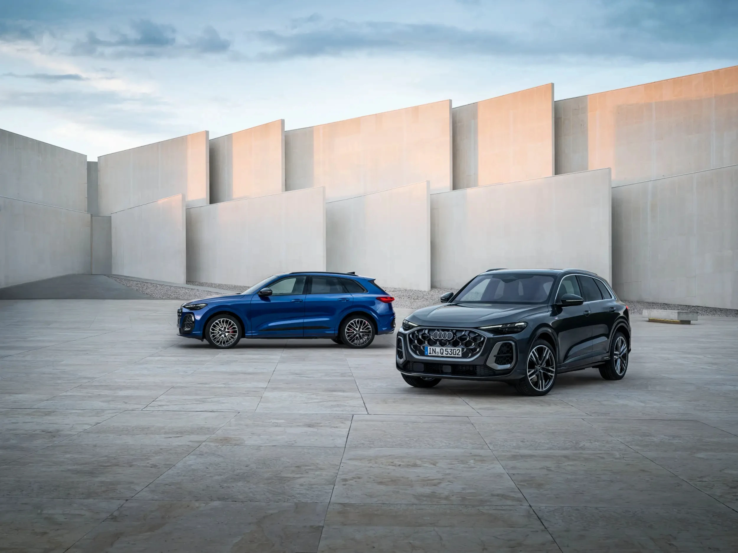 Dvě Audi Q5 nové generace zaparkovaná před moderní budovou