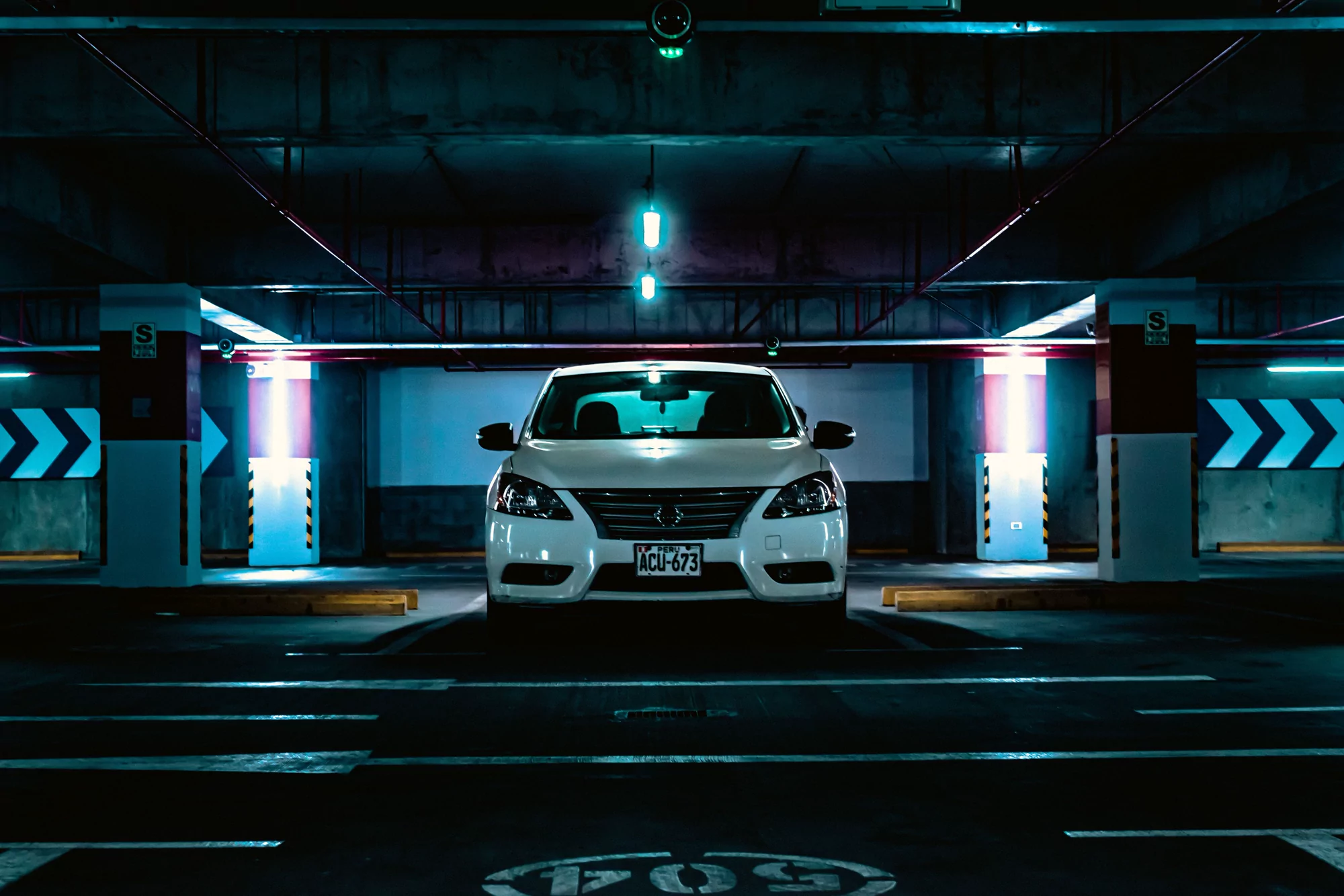 Bílý automobil zaparkovaný v podzemní garáži