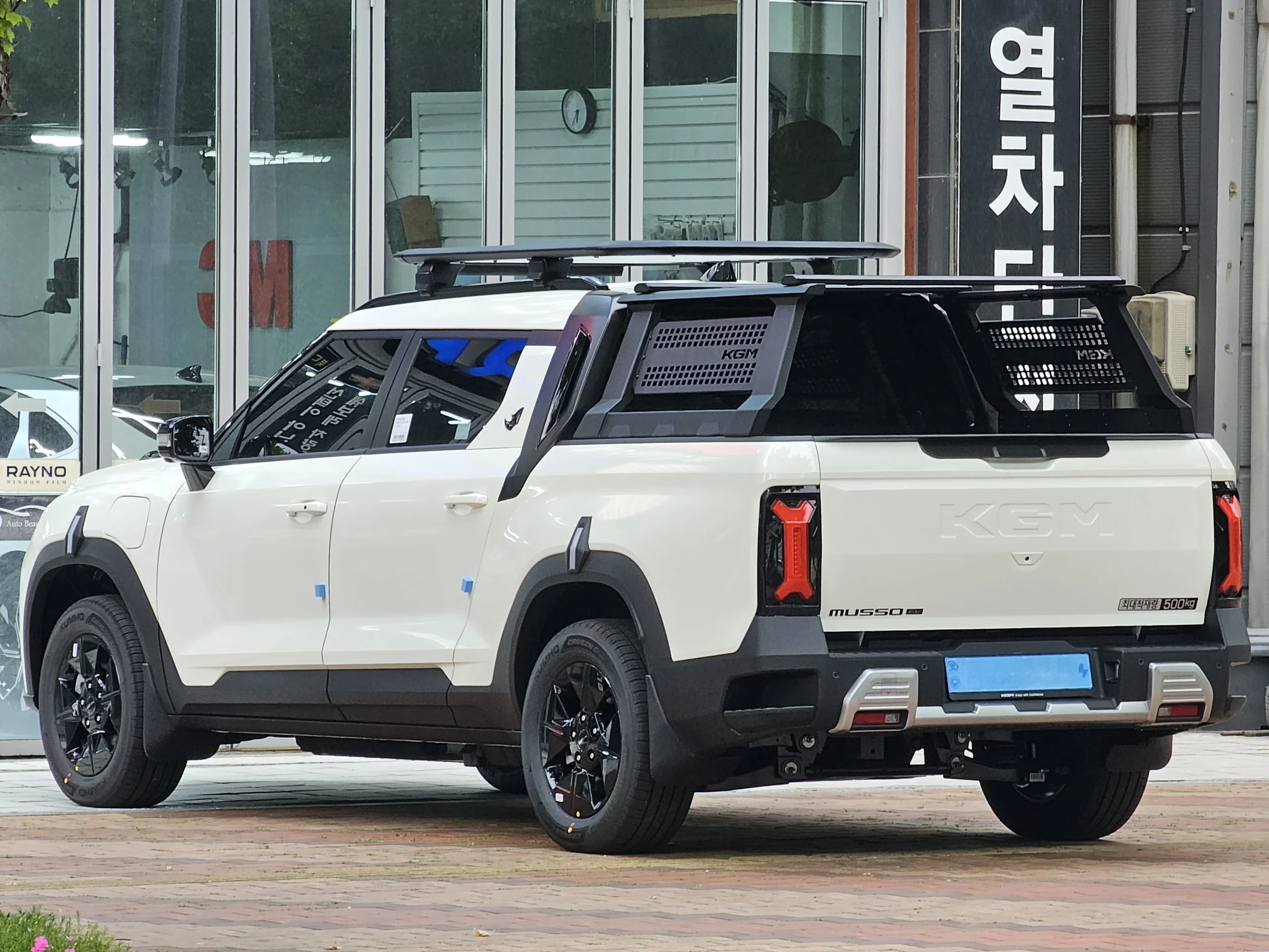 Zadní část elektrického pick-upu KGM Musso EV s korbou a nápisem KGM na sklápěcím víku