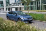 Modrý Volkswagen Golf Variant zepředu z boku před prosklenou budovou
