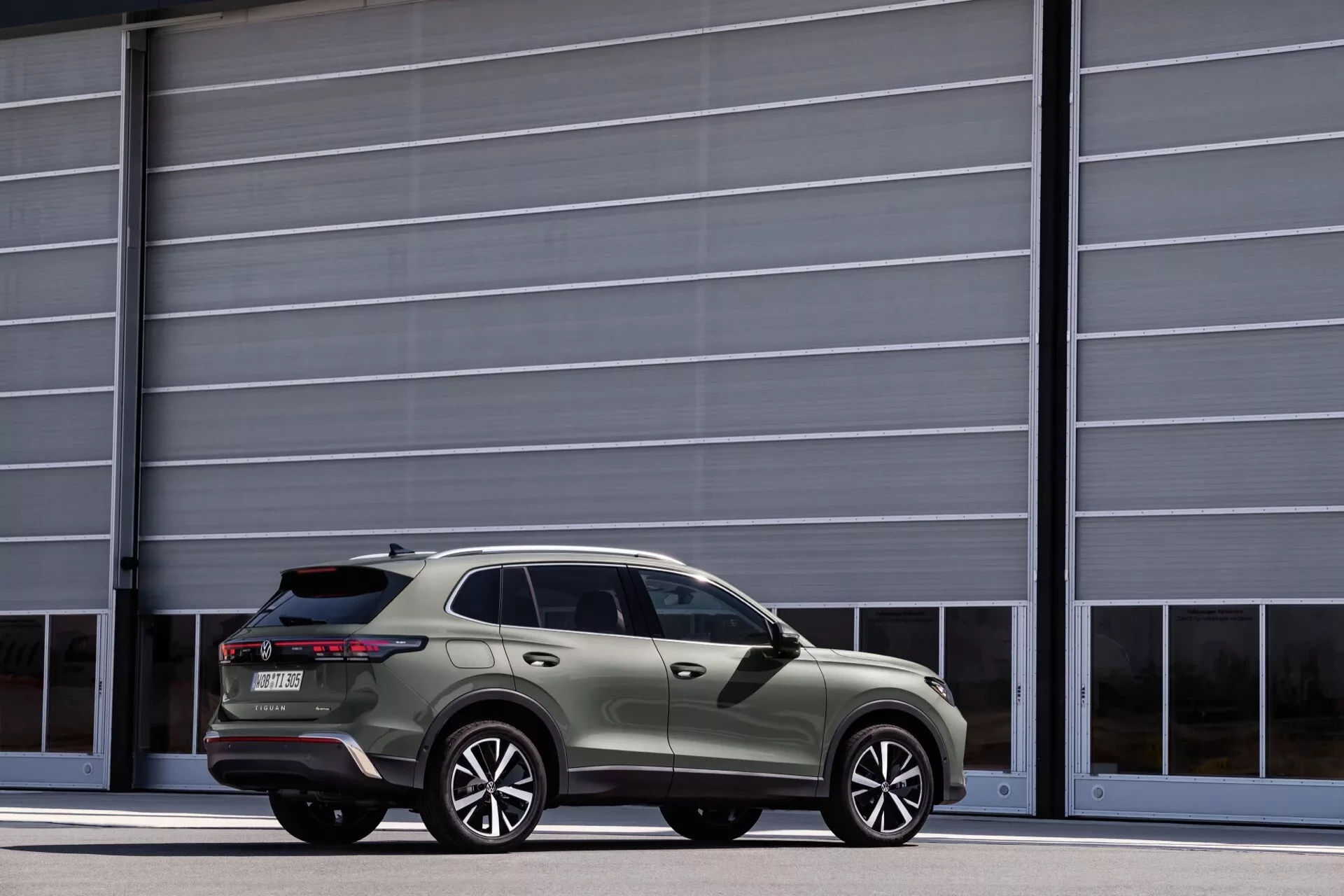 Zelený Volkswagen Tiguan zezadu z boku před halou, aktuální generace