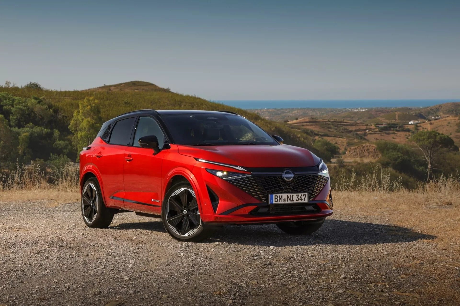 Nissan Qashqai e-POWER stojící v kopcovité krajině u pobřeží