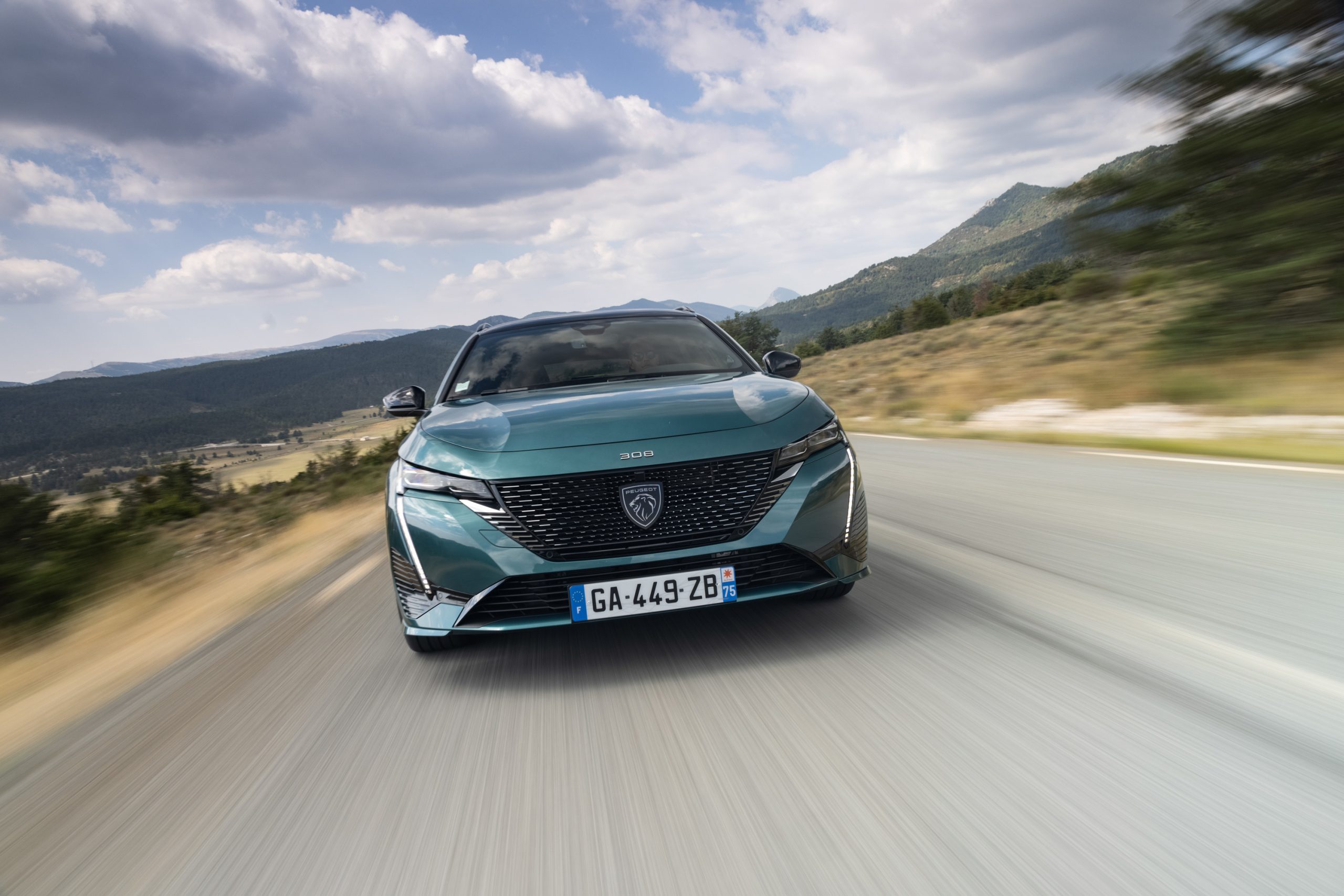 Současný zelený Peugeot 308 za jízdy z přední tříčtvrteční perspektivy