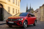 Volkswagen Taigo v červené barvě zaparkovaný v brněnské ulici s věžemi katedrály Petrov v pozadí