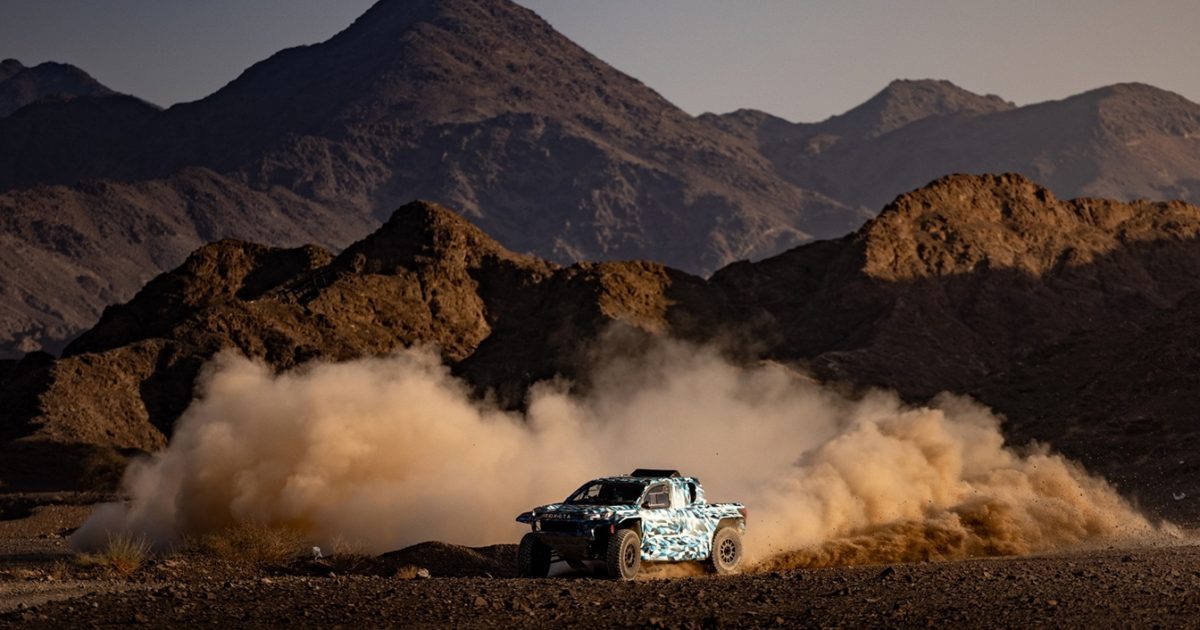 Vodíkový závodní speciál Toyota Hilux v maskovacím polepu při testech v poušti pro Rallye Dakar 2027