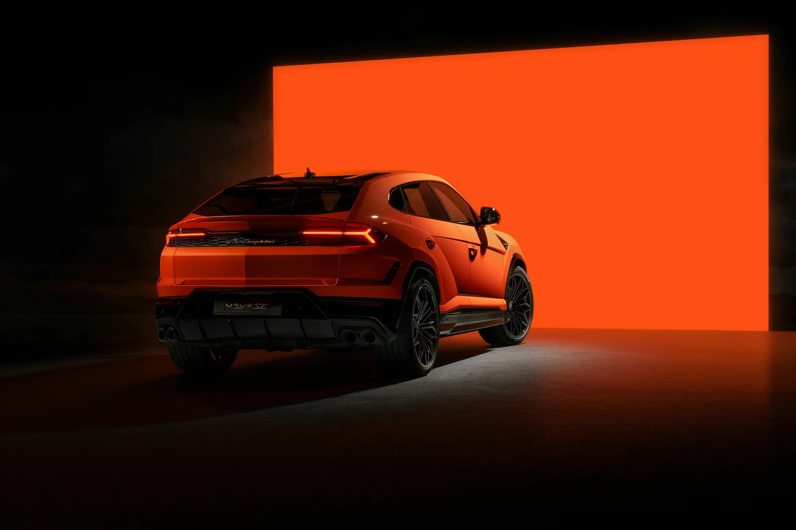 Oranžový Lamborghini Urus SE z pohledu na zadní a boční část karoserie