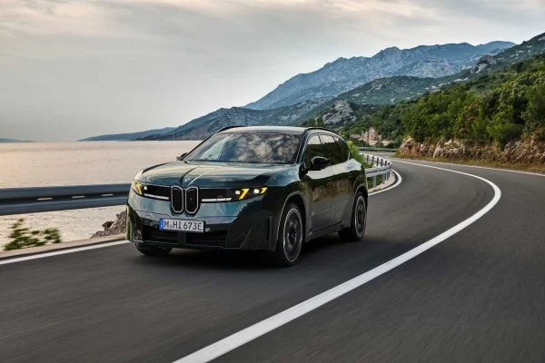 BMW iX3 M60 xDrive v zeleném laku při jízdě po pobřežní silnici