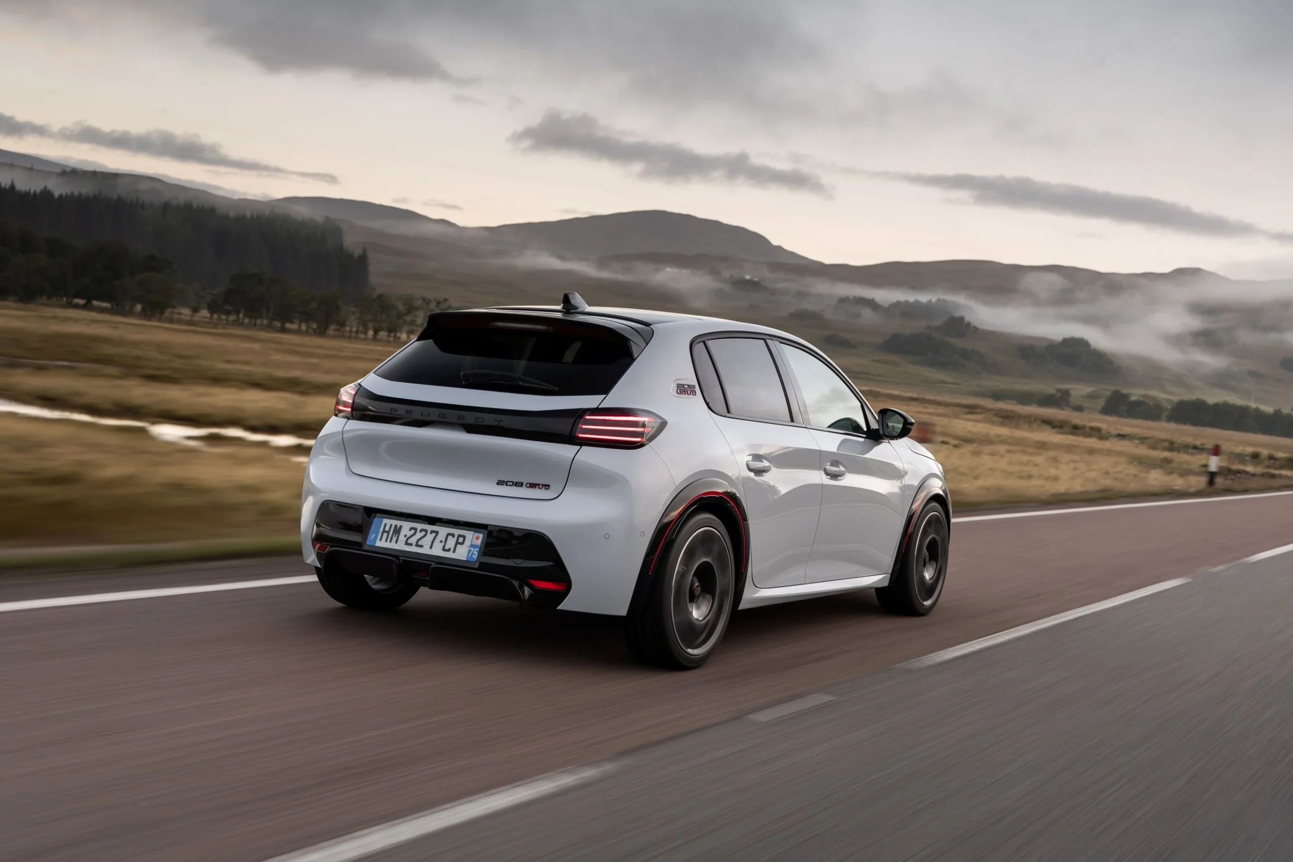 Peugeot E-208 GTi v bílé barvě zezadu při jízdě