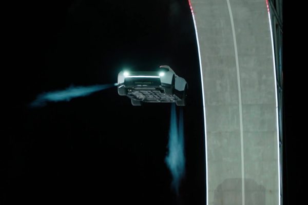 Tesla Roadster ve vzduchu vedle rampy s viditelnými proudy z trysek
